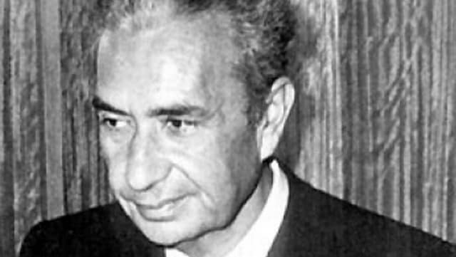 Foto in bianco e nero, dalla trama leggermente sgranata, di un primissimo piano dell'Onorevole Aldo Moro.  Lo sguardo è volto in basso a sinistra, fuori campo, e un sorriso è leggermente accennato