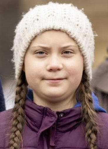 Greta Thunberg con una giacca a vento viola e le trecce che escono fuori dal cappello bianco