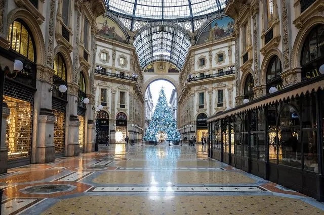 La Galleria Vittorio Emanuele deserta a Milano: l'albero di Natale al centro illuminato,  le serrande dei negozi abbassate, la galleria vuota.