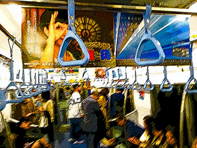 Immagine di un interno di un vagone con pannelli pubblicitari (Per leggerne la descrizione proseguire nel link). Primo piano sulle maniglie per i passeggeri.