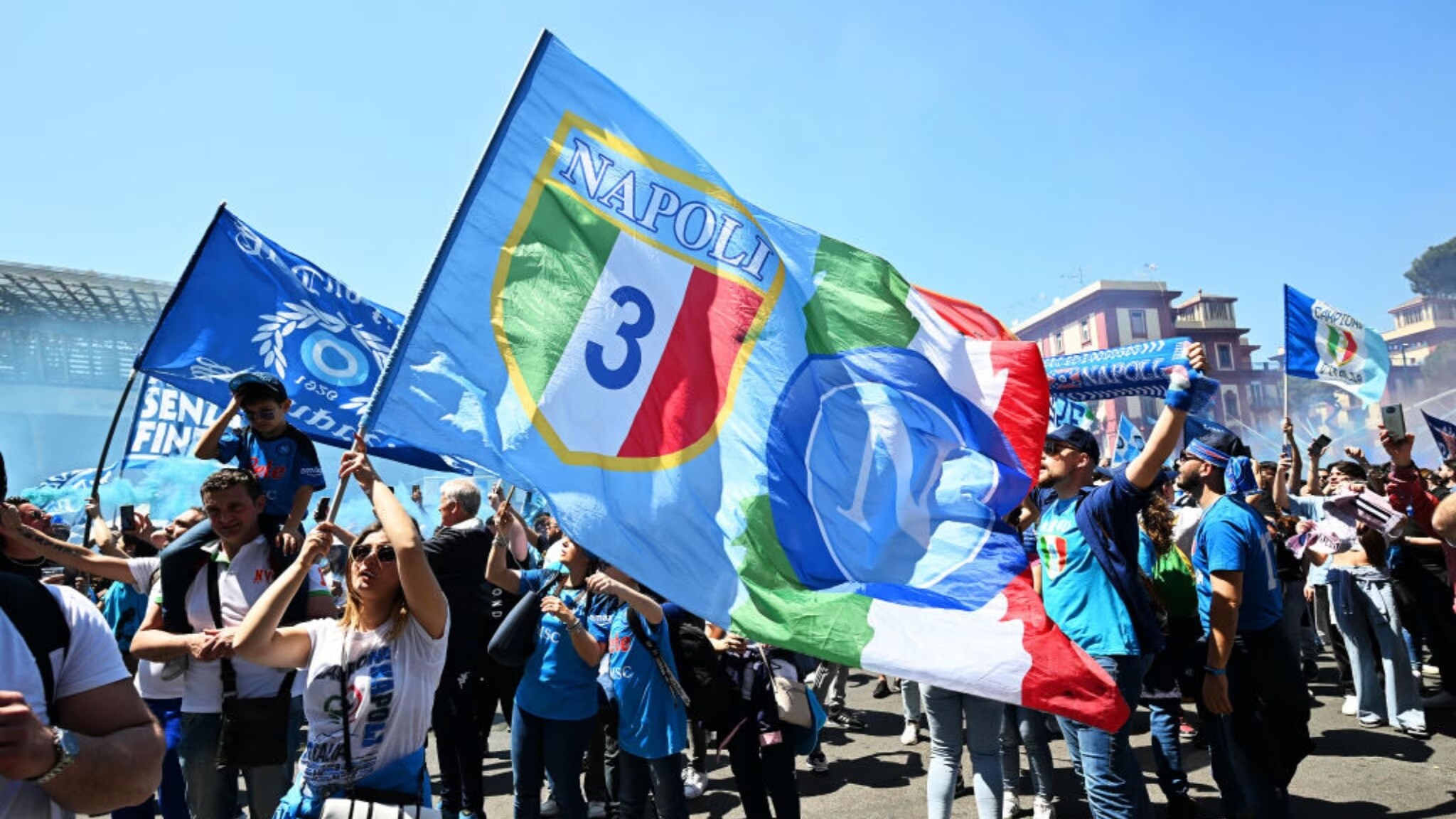 Festeggiamenti dei tifosi del Napoli che sventolano bandiere e striscioni.