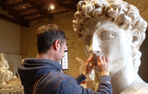 Un uomo esplora col tatto una scultura al Museo Omero